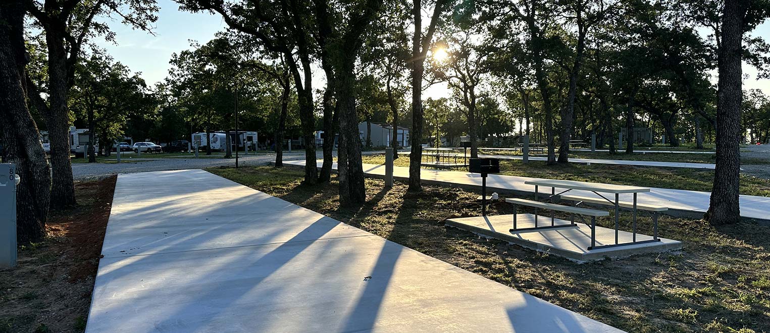 Concrete RV pads at Hog Mountain RV Ranch in evening light, with oak trees and picnic tables