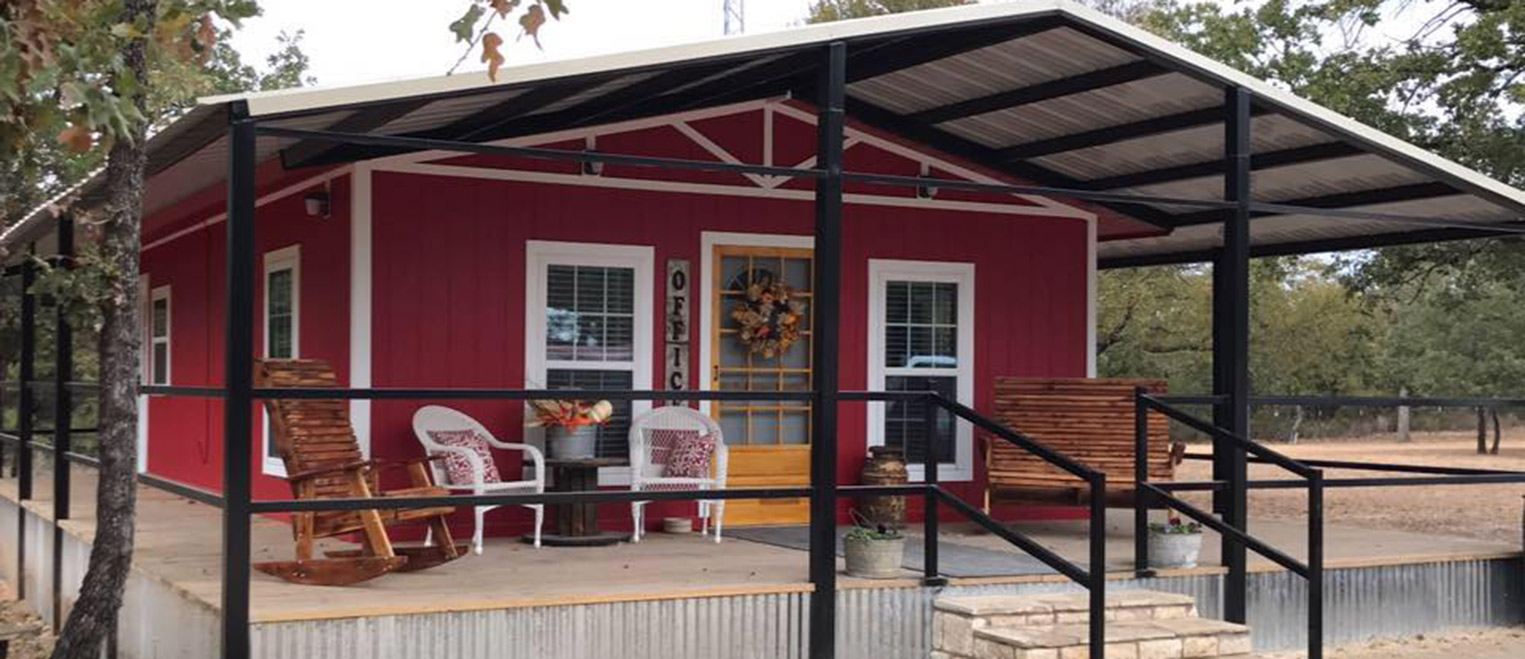 The red barn-style office building at Hog Mountain RV Ranch, with a covered porch, rocking chairs and a wreath on the door